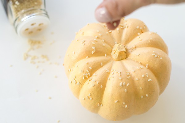 Someone putting seeds on a pumpkin