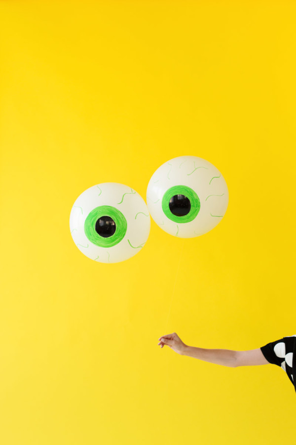 Someone holding eyeball balloons in front of a yellow wall