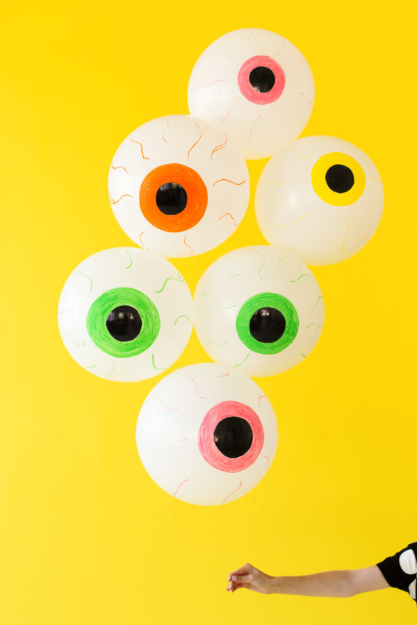 Eyeball balloons in front of a yellow wall