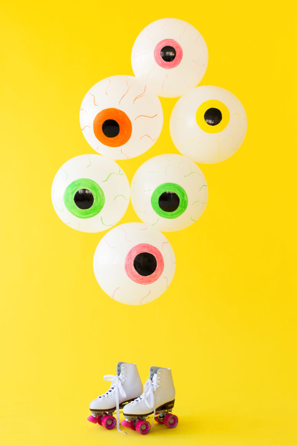 Eyeball balloons in front of a yellow wall