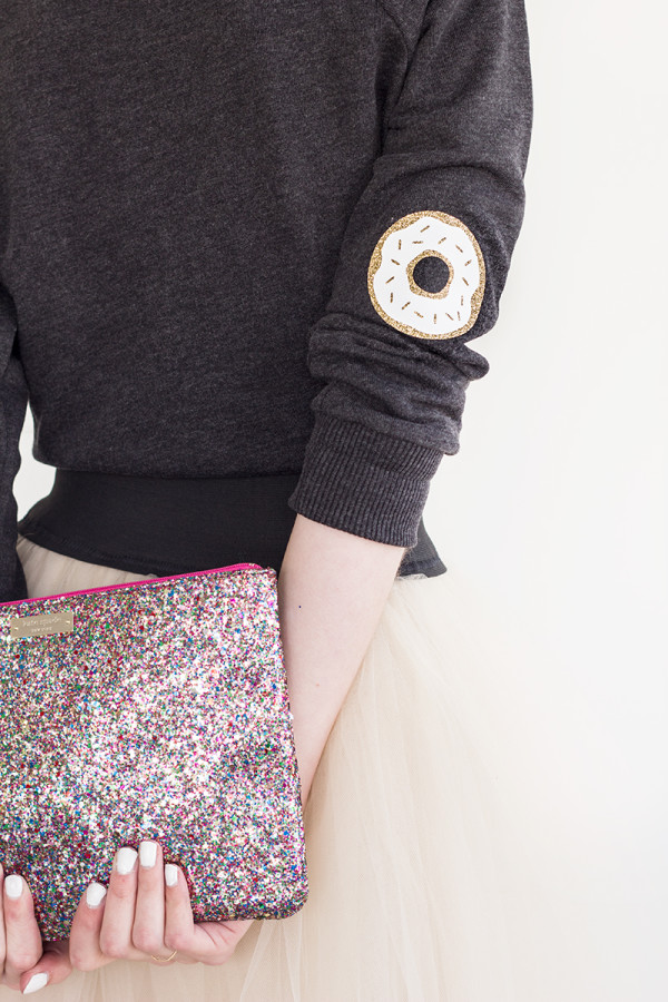 The back of someone wearing a sweater and skirt and holding a clutch