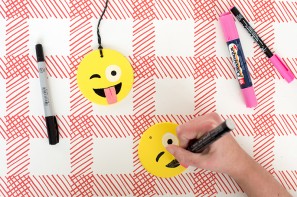 Someone drawing an emoji face on a ornament