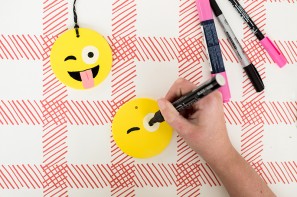 Someone drawing an emoji face on a ornament