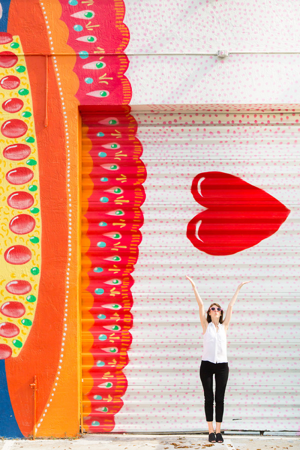 A woman in front of a red and yellow mural