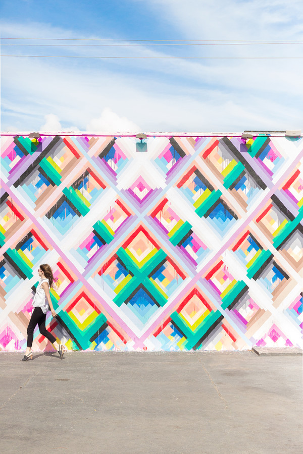 A woman in front of a colorful mural