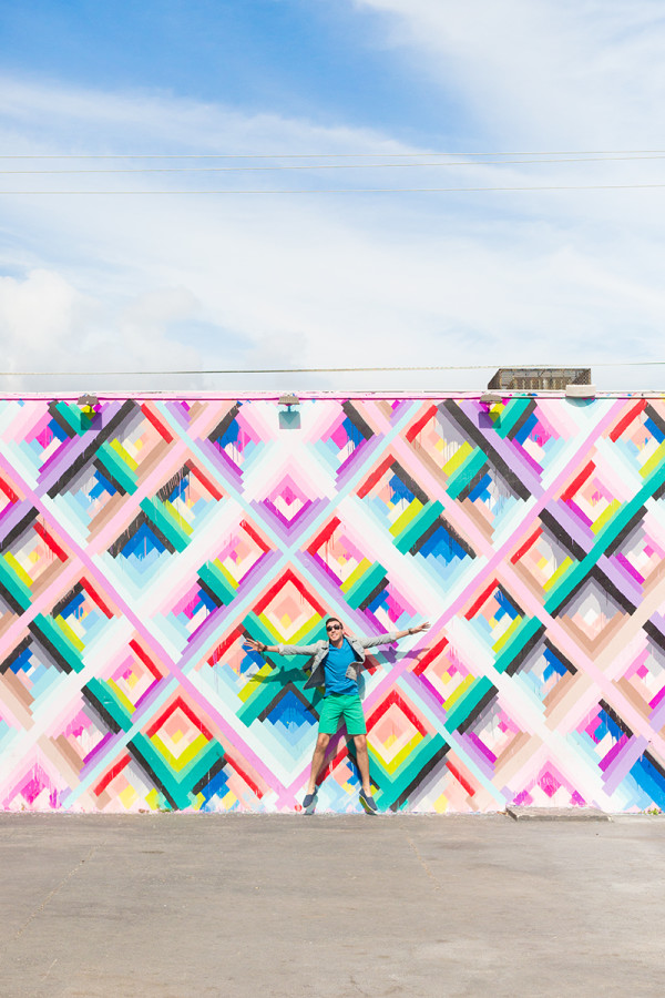 A man in front of a colorful mural