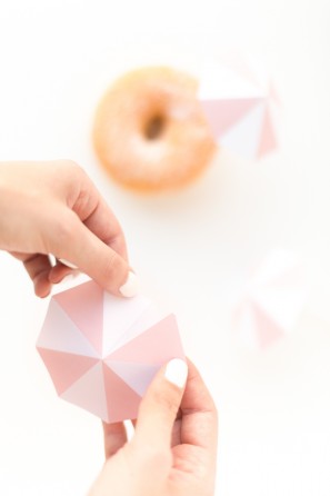 Someone putting a little umbrella on a donut