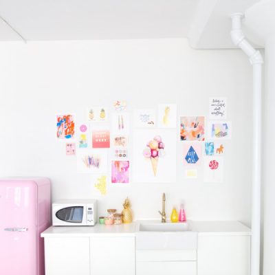 A kitchen with posters and a pink fridge