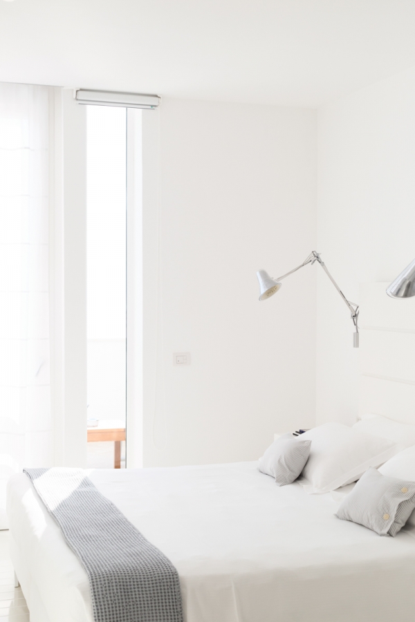 A bedroom with a white bed and a window