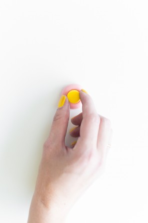 A woman putting a yellow dot on a pink snack