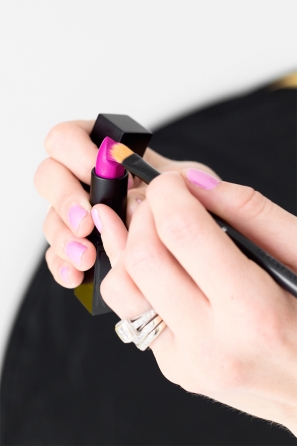 Someone putting lipstick on a brush