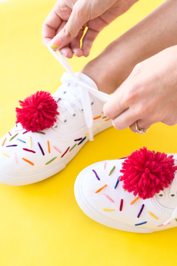 White sneakers with rainbow string and red pom poms