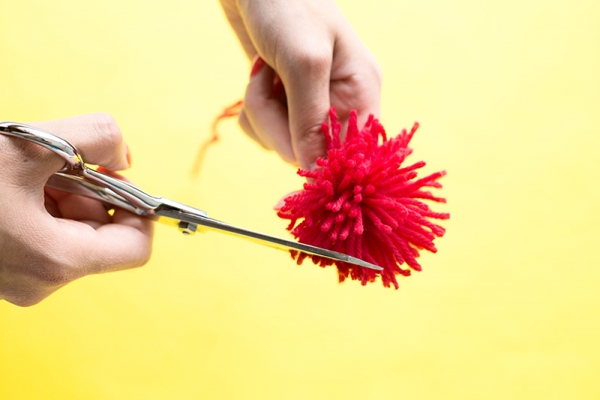 Someone cutting a red pom pom
