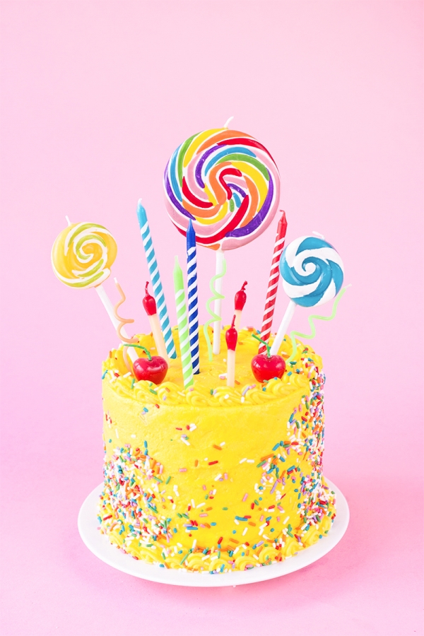 A yellow cake with lollipops and candles