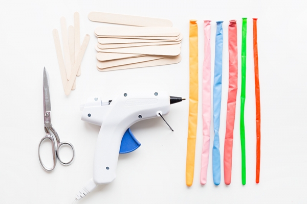 Glue gun, wood sticks, and rainbow balloons
