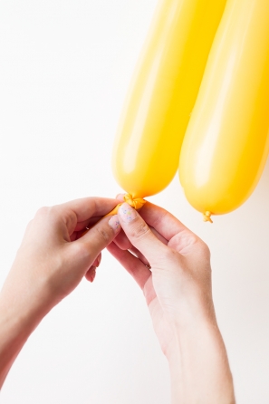 Someone tying a yellow balloon
