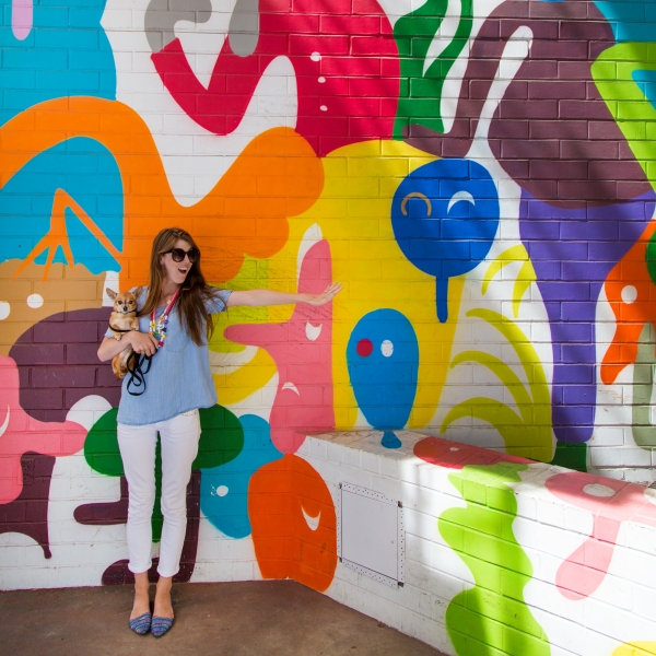 A woman in front of a colorful mural