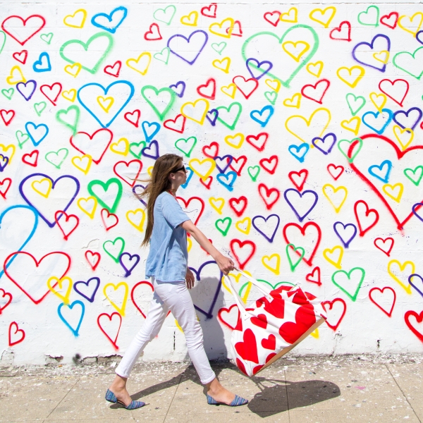 A woman in front of a rainbow heart mural