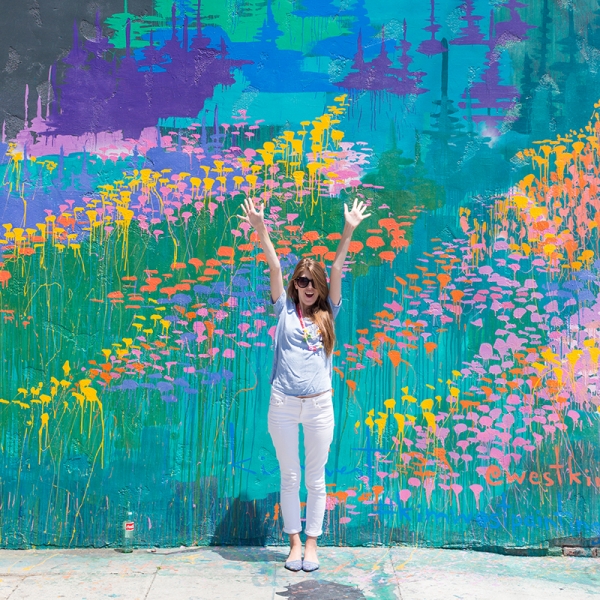 A woman standing in front of a colorful mural