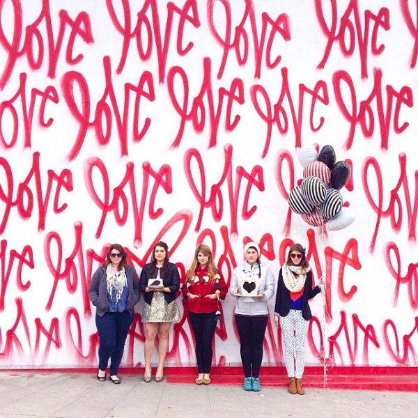 A group of people in front of a red mural