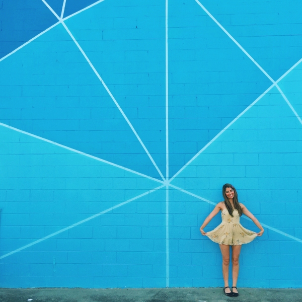 A woman standing in front of a blue mural