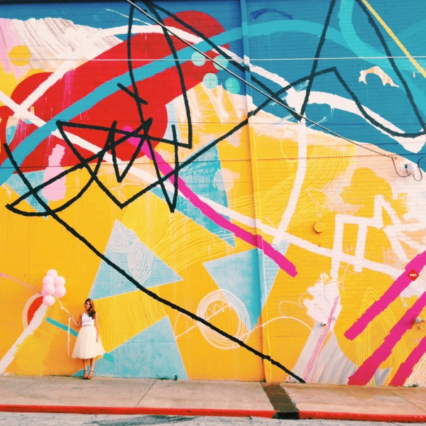 A woman standing in front of a colorful mural