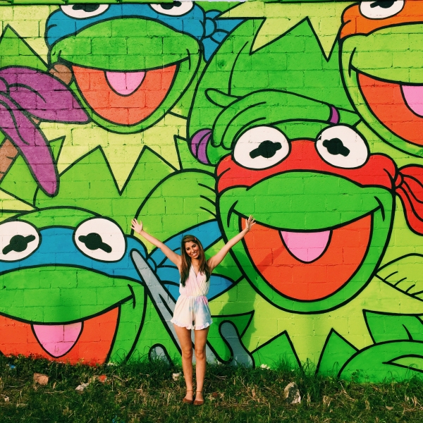 A woman standing in front of a colorful mural