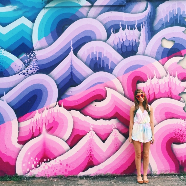 A woman standing in front of a colorful mural