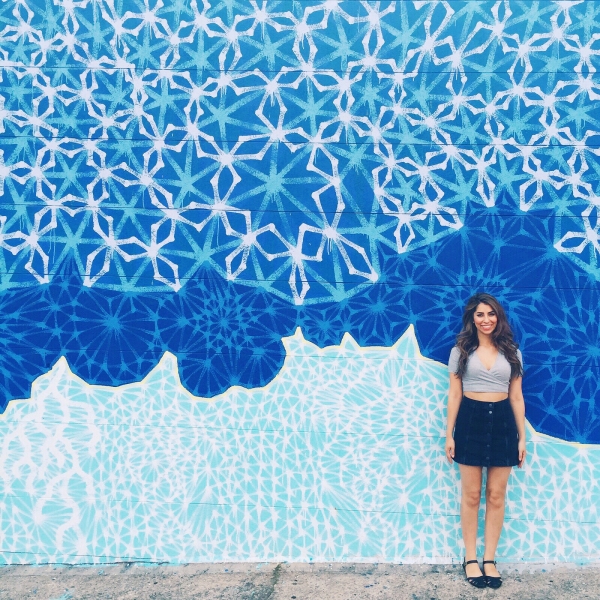 A woman standing in front of a blue mural