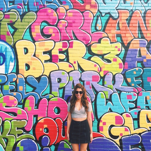 A woman standing in front of a colorful mural