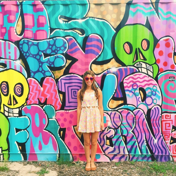 A woman standing in front of a colorful mural