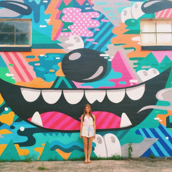 A woman standing in front of a colorful mural
