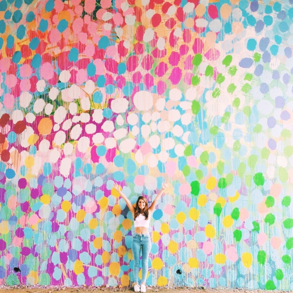 A woman standing in front of a colorful mural