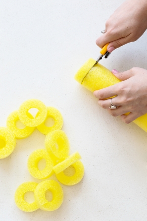 Someone cutting colorful pool noodles