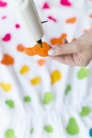 Someone gluing orange felt on a white shirt