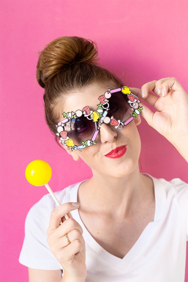 Someone wearing glasses and holding a lollipop 