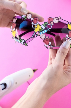 Someone holding sunglasses and a glue gun