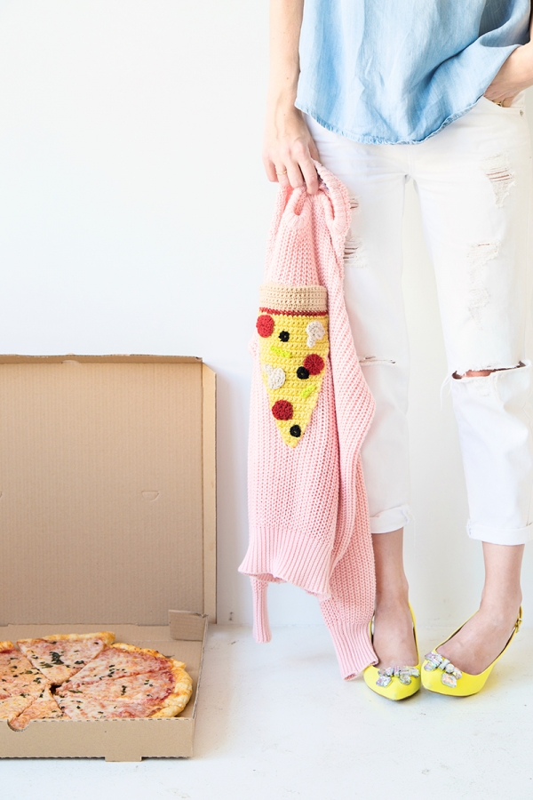 Someone holding a pizza sweater and a box of pizza next to it