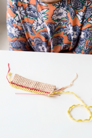 Someone sewing something beige, red, and yellow