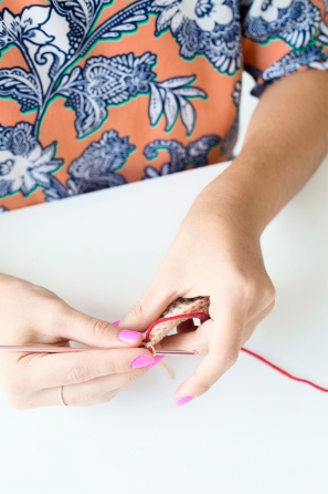 Someone sewing something beige and red