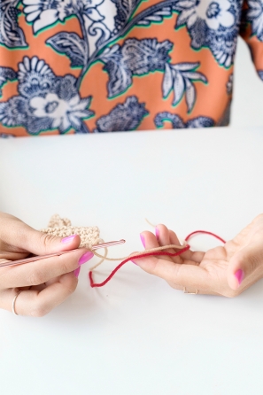 Someone sewing something beige and red