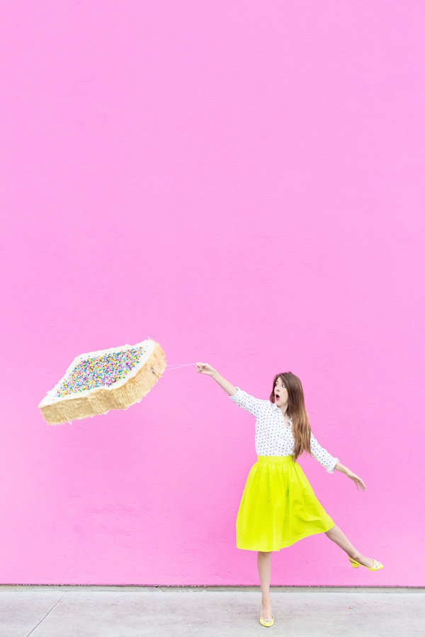 A woman in a yellow skirt and holding a fairy bread pinata