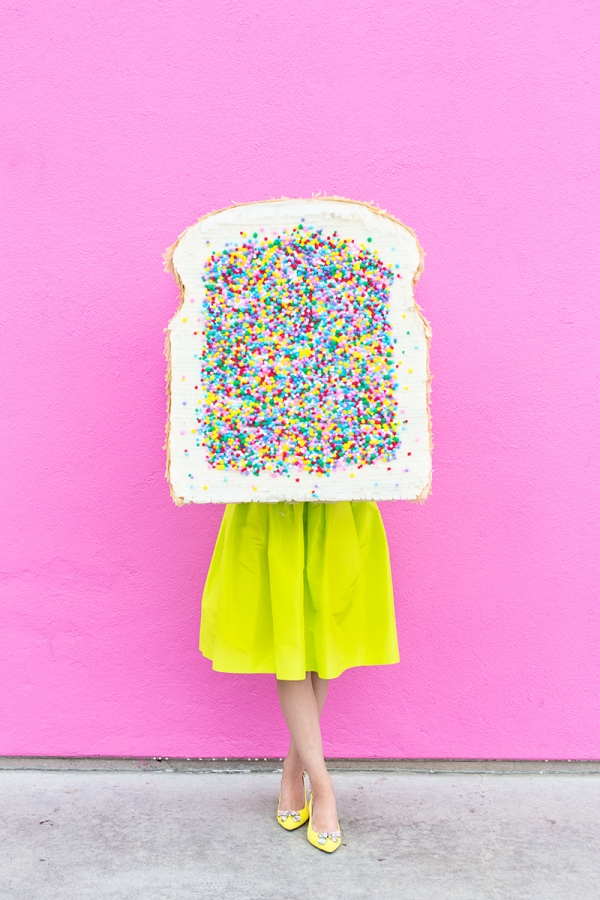 A woman in a yellow skirt and holding a fairy bread pinata