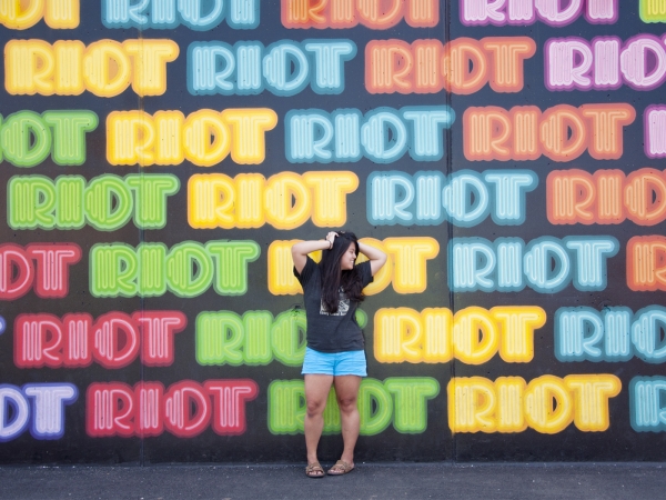 A woman standing in front of a colorful mural