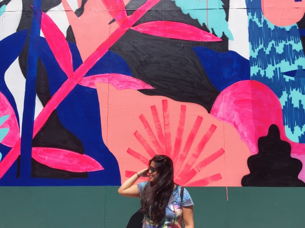 A woman standing in front of a colorful mural