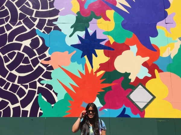 A woman standing in front of a colorful mural