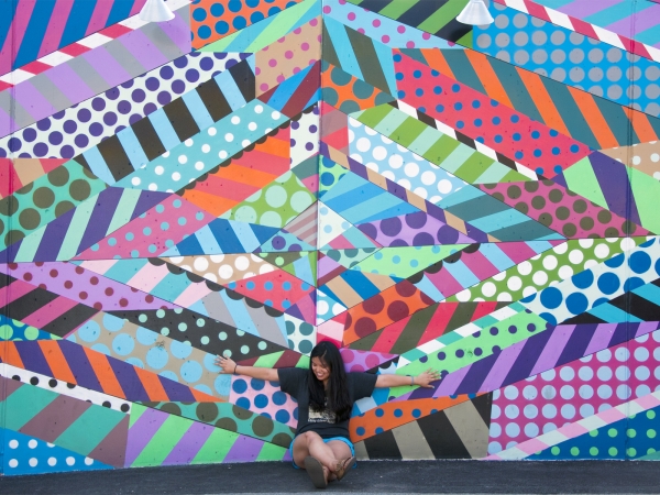 A woman standing in front of a colorful mural 