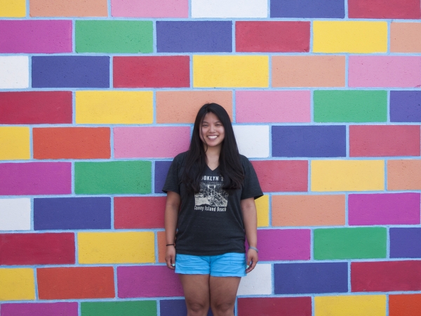 A woman standing in front of a colorful mural