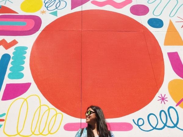 A woman standing in front of a colorful mural