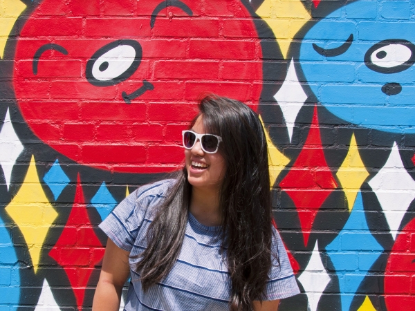 A woman standing in front of a colorful mural